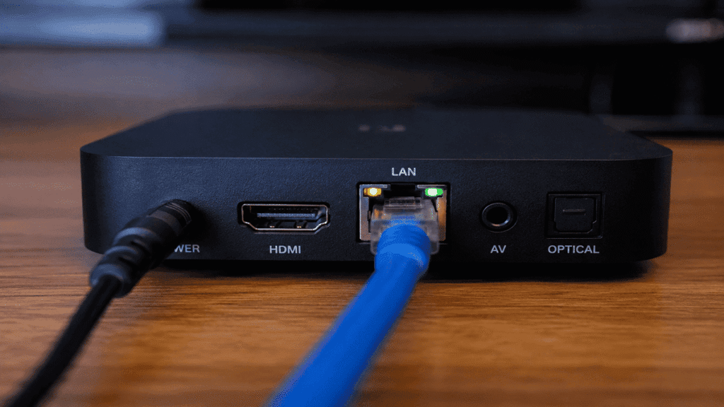 Cabo de rede Ethernet azul conectado na porta LAN de uma TV Box para garantir estabilidade no streaming 4K